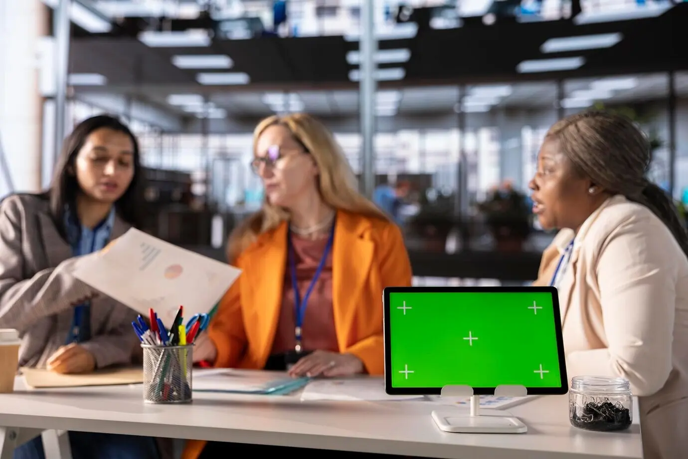 Geschäftsfrauen verschiedener ethnischer Herkunft arbeiten neben einem isolierten Greenscreen.